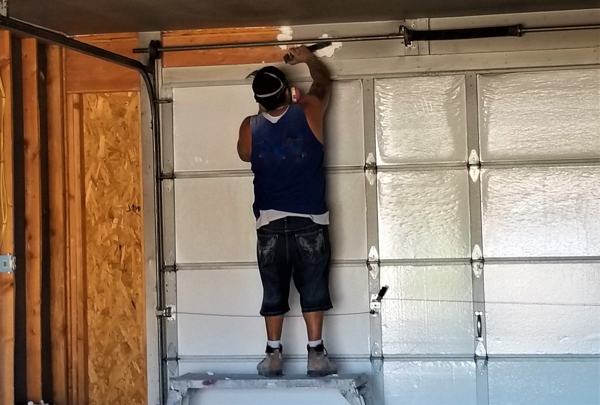 construction worker installing a roll up garage door in a garage